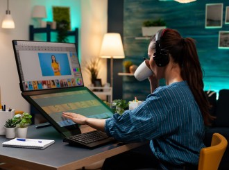 Woman with editor occupation wearing headphones at studio office desk. Professional graphic artist working on picture editing background for template using touchpad monitor screen